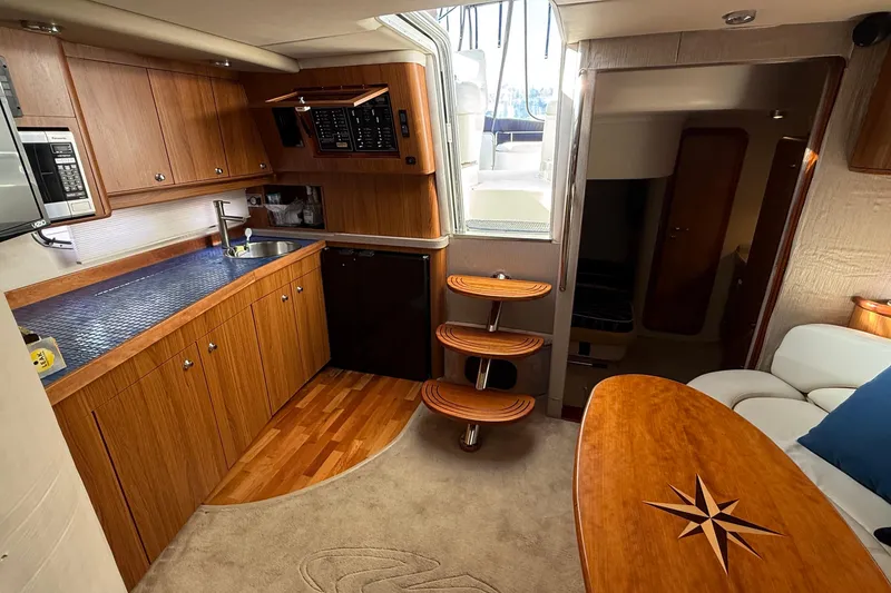 Slide: The Image of 2003 Regal Commodore 4260 yacht interior with wooden cabinetry, kitchenette, and cozy seating area. - 39
