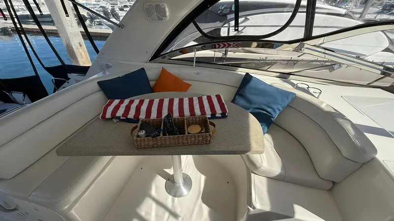 Slide: The Image of 2003 Regal Commodore 4260 yacht interior with cushioned seating, table, and decorative pillows. - 5