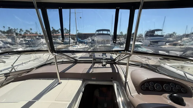 Slide: The Image of 2003 Regal Commodore 4260 yacht cockpit view in marina, showcasing dashboard and surrounding boats. - 7