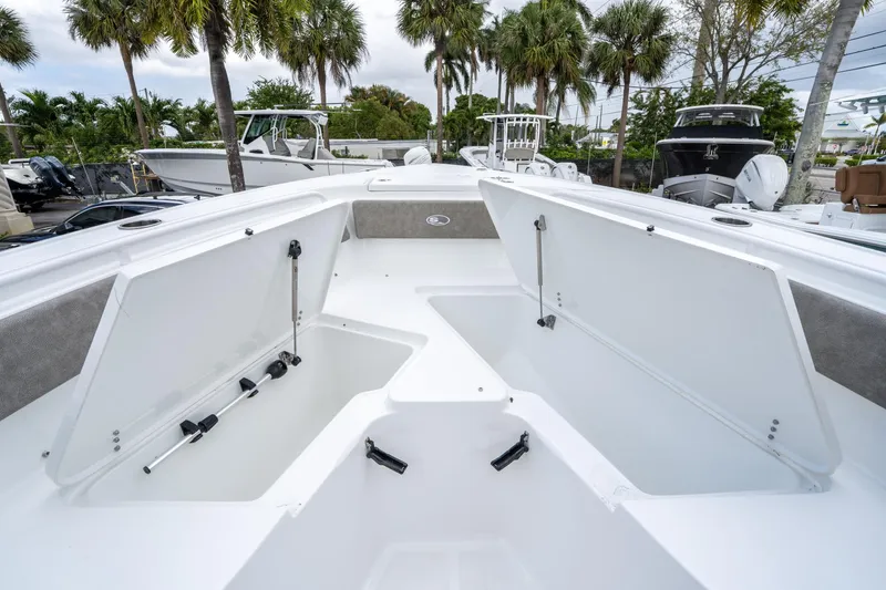 Slide: The Image of 2025 Sea Hunt Ultra 245 SE boat with open storage compartments, surrounded by palm trees. - 35