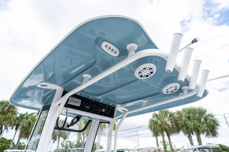 Slide: The Image of 2025 Sea Hunt Ultra 245 SE boat T-top with rod holders and speakers, under a cloudy sky. - 21