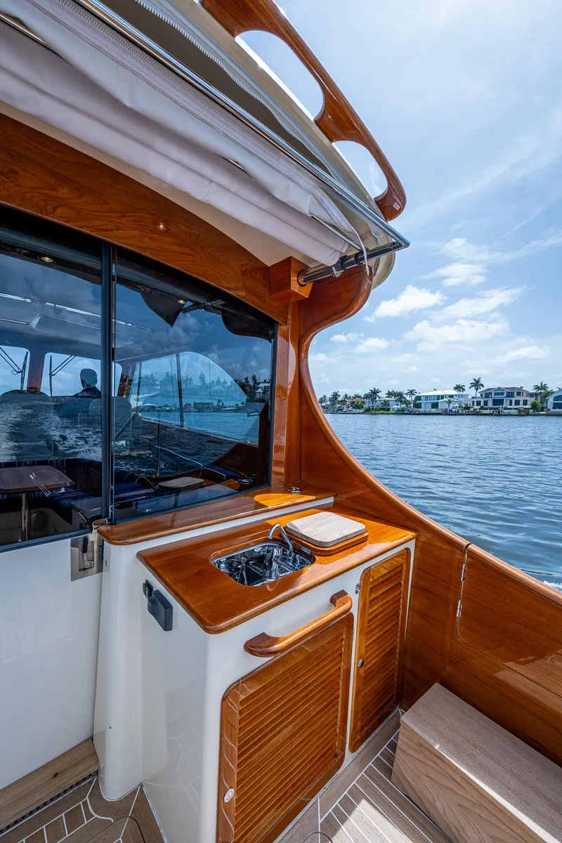 Slide: The Image of Hinckley Talaria 43 Motoryacht 2021, elegant wood finish, docked by waterfront homes. - 31