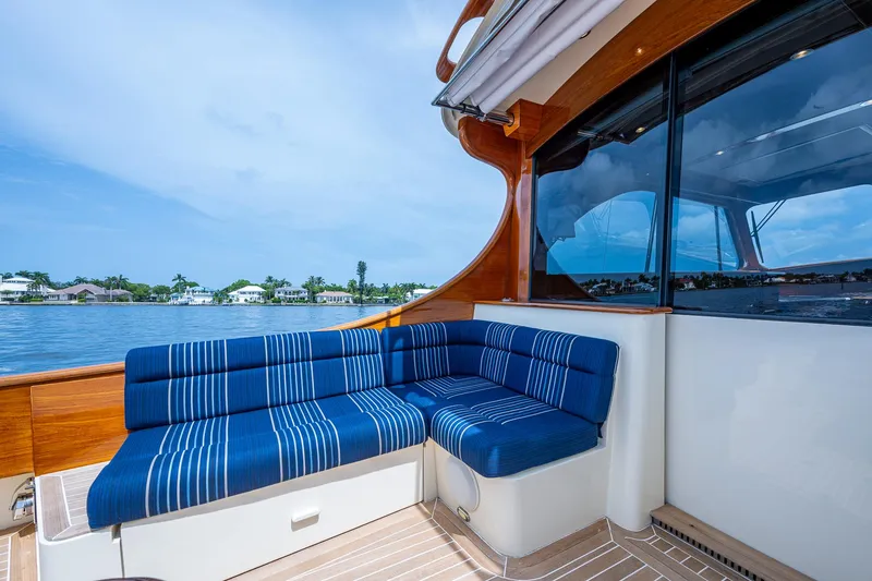 Slide: The Image of Hinckley Talaria 43 Motoryacht 2021 with blue-striped seating, overlooking serene waterfront. - 33