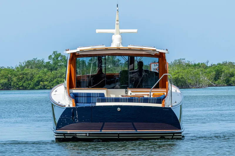 Slide: The Image of Hinckley Talaria 43 Motoryacht 2021 on calm water, rear view with lush greenery. - 2