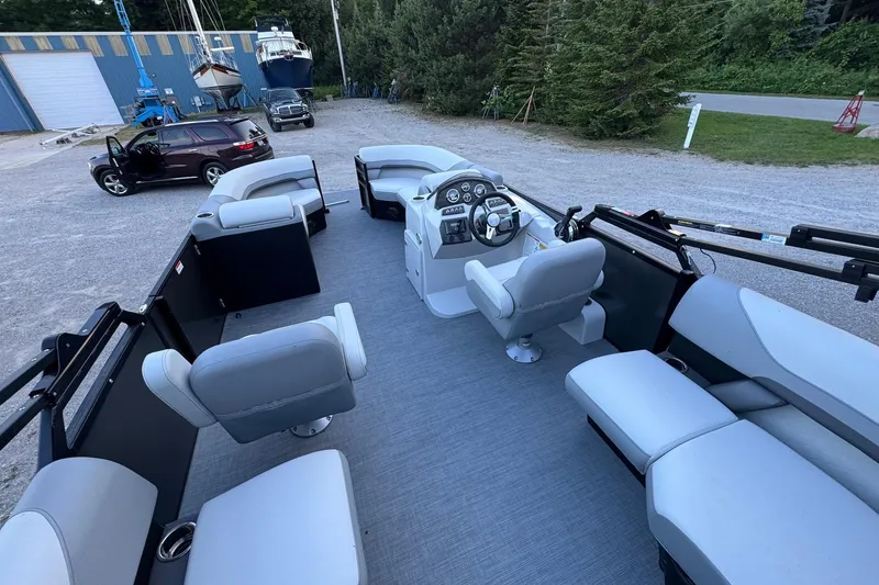 Slide: The Image of 2025 Lowe SS230WV pontoon boat with spacious seating, parked near a blue building. - 4