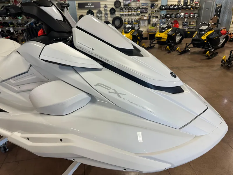 Slide: The Image of 2025 Yamaha WaveRunner FX Cruiser SVHO in showroom, sleek white design, surrounded by snowmobiles. - 2