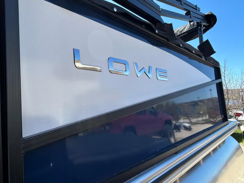 Slide: The Image of Lowe LS210WT 2025 boat with motor, parked near buildings and vehicles. - 5