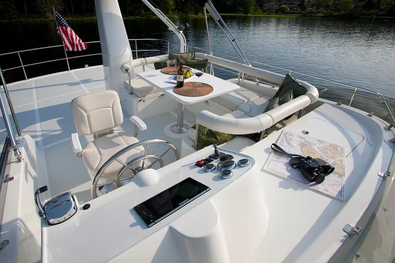 Slide: The Image of Helmsman Trawlers 43E PILOTHOUSE 2026 yacht deck with seating, table, and navigation tools. - 10