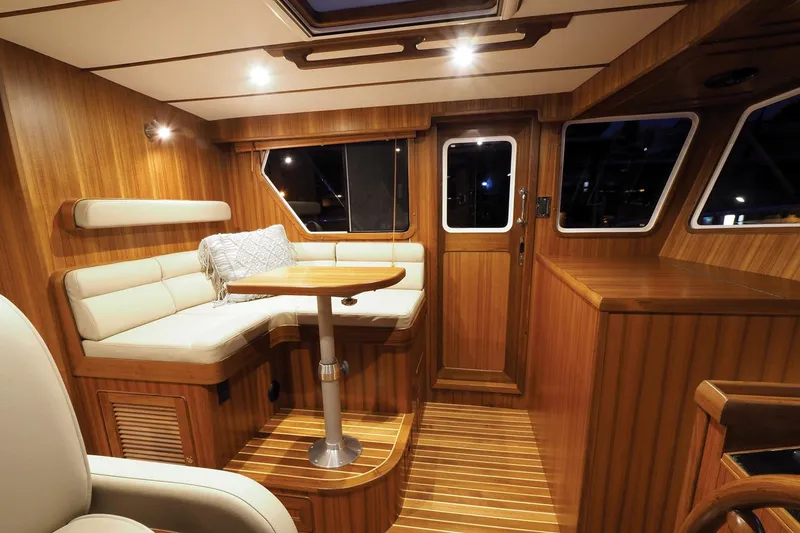 Slide: The Image of Luxurious interior of 2026 Helmsman Trawlers 43E Pilothouse with wood finish and seating area. - 33