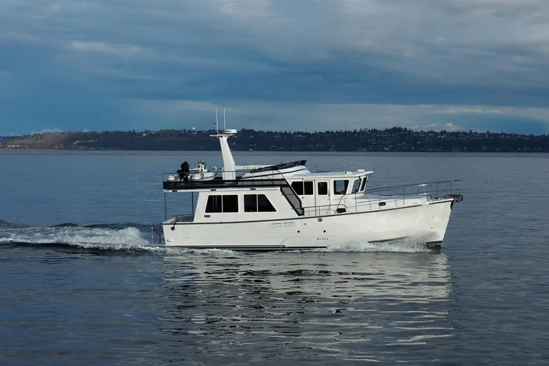 Slide: The Image of 2026 Helmsman Trawlers 43E Pilothouse cruising on calm waters under cloudy skies. - 8