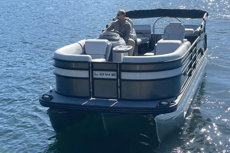 Slide: The Image of 2025 Lowe SS230WT pontoon boat on water with driver. - 2