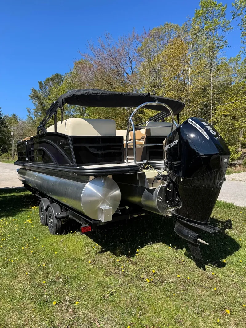 Slide: The Image of 2025 Lowe SS250WT pontoon boat on trailer, parked on grass under clear blue sky. - 2