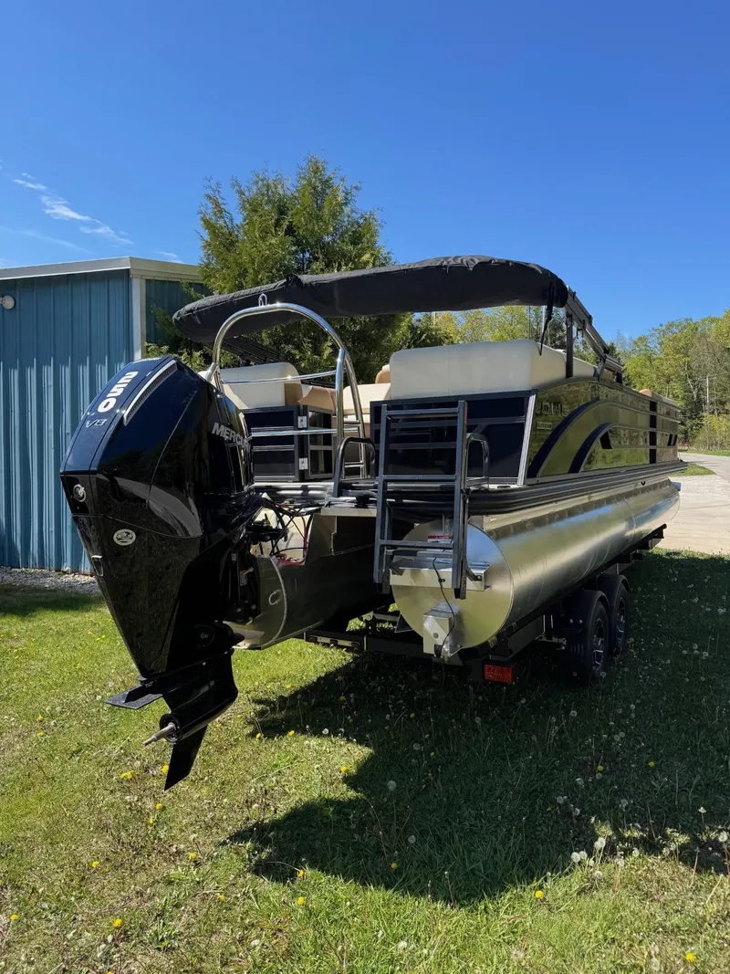 Slide: The Image of 2025 Lowe SS250WT pontoon boat on trailer, parked on grass with trees in background. - 3