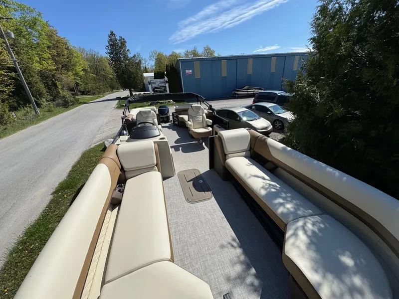 Slide: The Image of 2025 Lowe SS250WT pontoon boat with beige seating and modern helm, parked on a road. - 5