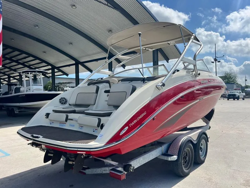 Slide: The Image of 2014 Yamaha Boats 242 Limited S on trailer, red and white, parked outdoors. - 11