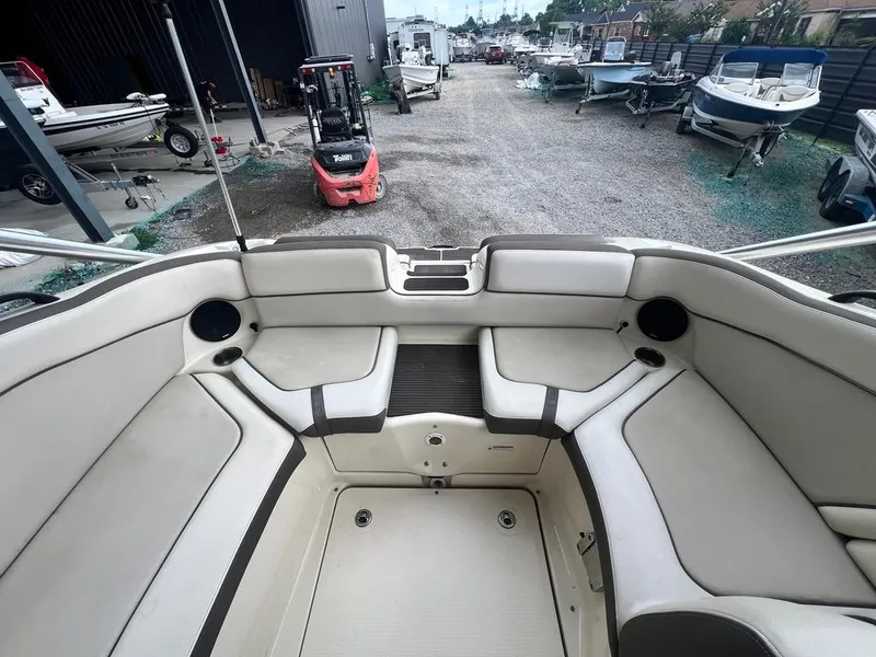 Slide: The Image of 2014 Yamaha Boats 242 Limited S interior, spacious seating, docked with other boats in background. - 16