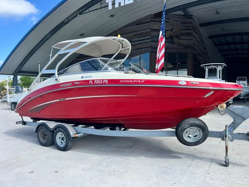 Slide: The Image of 2014 Yamaha Boats 242 Limited S in red on a trailer, parked outdoors. - 3