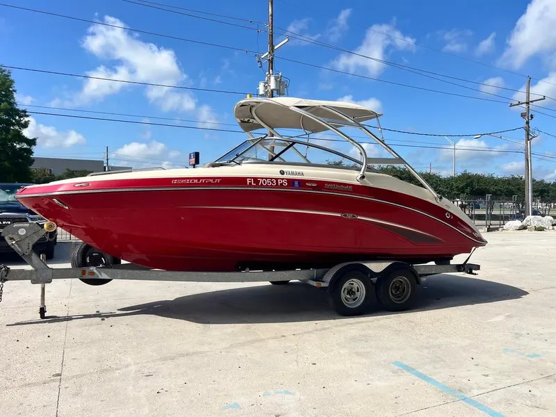 Slide: The Image of 2014 Yamaha Boats 242 Limited S in red on a trailer, parked outdoors. - 7