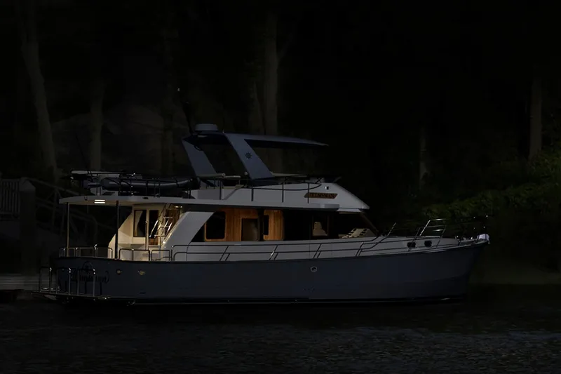 Slide: The Image of 2026 Helmsman Trawlers 43 Sedan yacht illuminated at night on the water. - 6