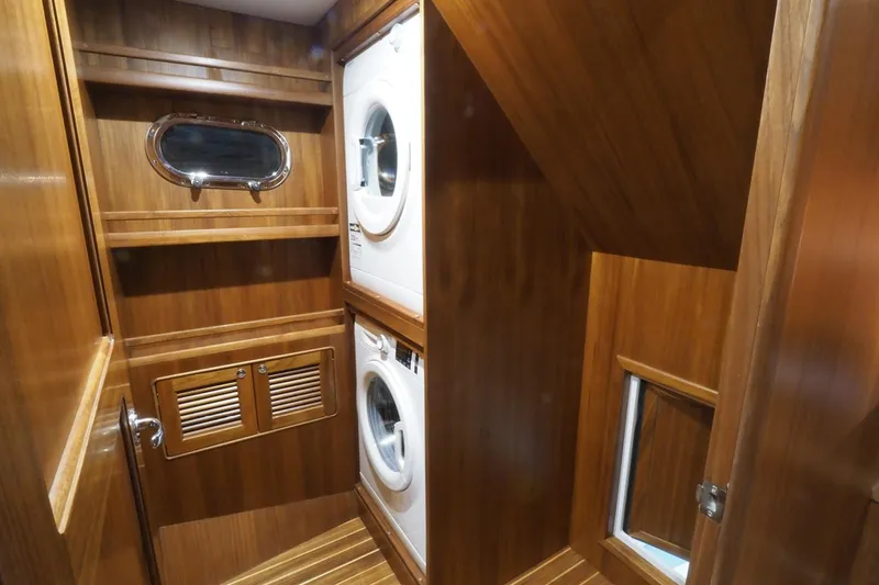 Slide: The Image of Laundry area in 2026 Helmsman Trawlers 46 Pilothouse with wood paneling and stacked washer-dryer. - 49