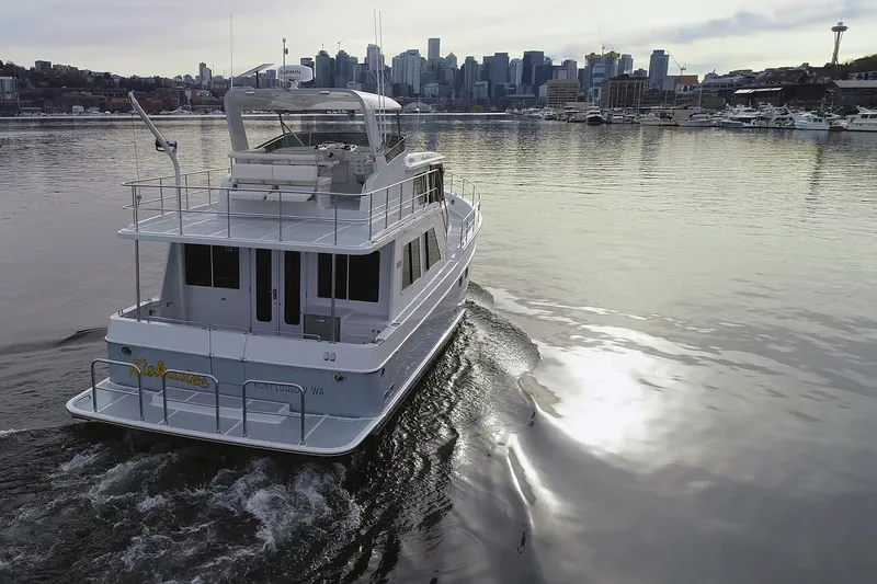 Slide: The Image of 2026 Helmsman Trawlers 46 Pilothouse cruising near city skyline on calm water. - 6
