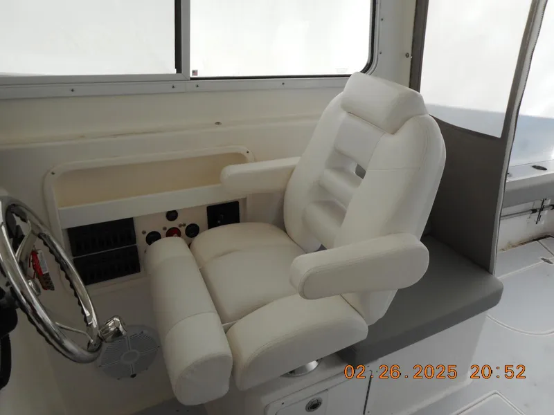 Slide: The Image of 2024 NorthCoast 255HT boat interior with white captain's chair and steering wheel. - 33