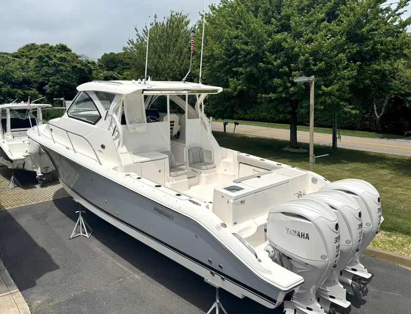 The Image of 2025 Pursuit OS 355 Offshore boat with triple Yamaha engines, parked outdoors. - 0