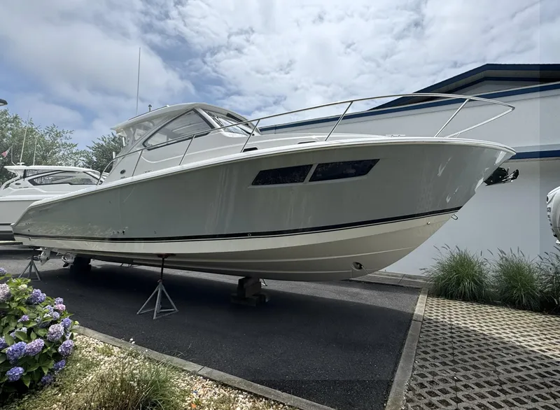 Slide: The Image of 2025 Pursuit OS 355 Offshore boat displayed outdoors on stands. - 2