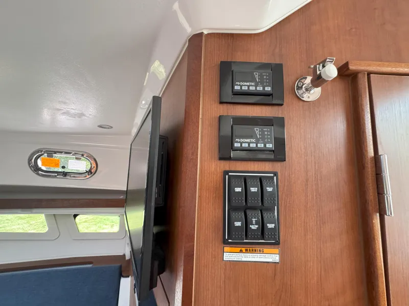 Slide: The Image of Control panel inside 2025 Pursuit OS 355 Offshore boat cabin with switches and display. - 26