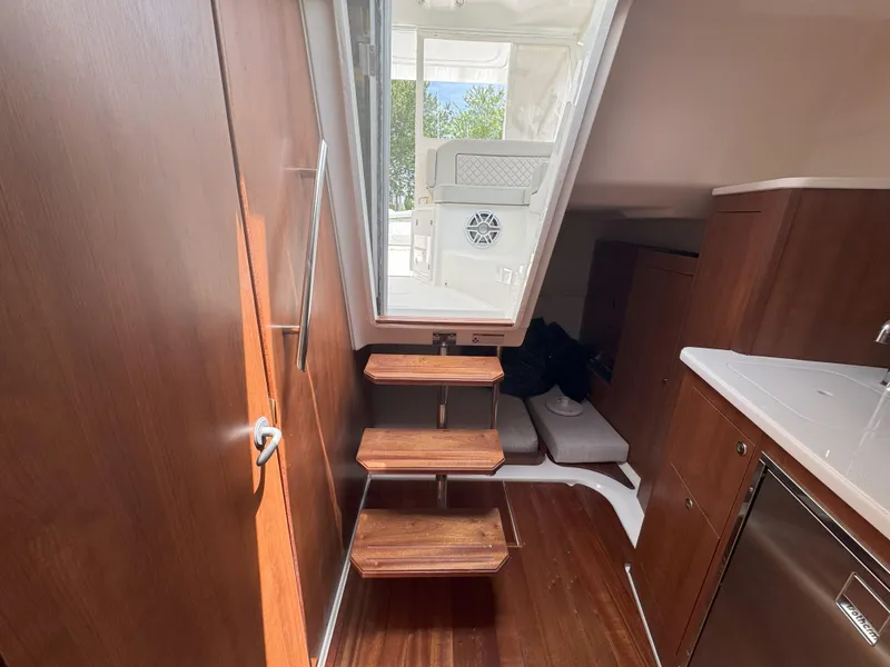 Slide: The Image of Interior of 2025 Pursuit OS 355 Offshore boat with wooden steps and modern cabinetry. - 30