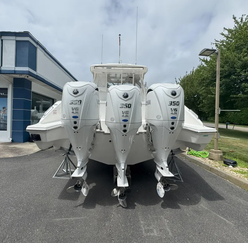 Slide: The Image of 2025 Pursuit OS 355 Offshore boat with triple Yamaha 350 V6 engines, parked outdoors. - 4