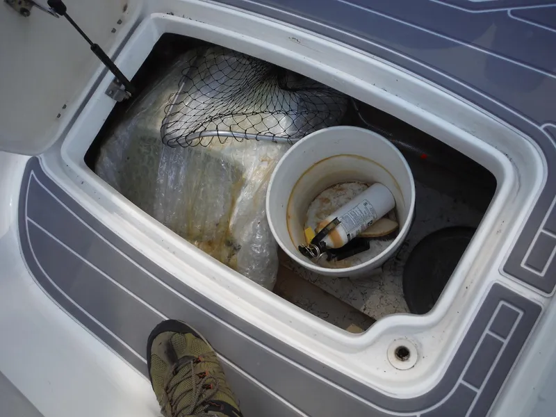 Slide: The Image of Storage compartment of 2019 Hurricane Center Console 21 OB with fishing gear and bucket. - 15