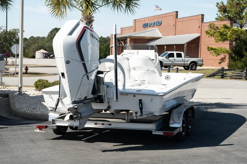Slide: The Image of 2025 Turner Boatworks 24 SAVAGE on trailer, parked near a building with palm trees. - 5