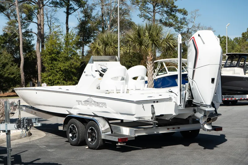 Slide: The Image of 2025 Turner Boatworks 24 SAVAGE on trailer, parked outdoors with trees in background. - 7