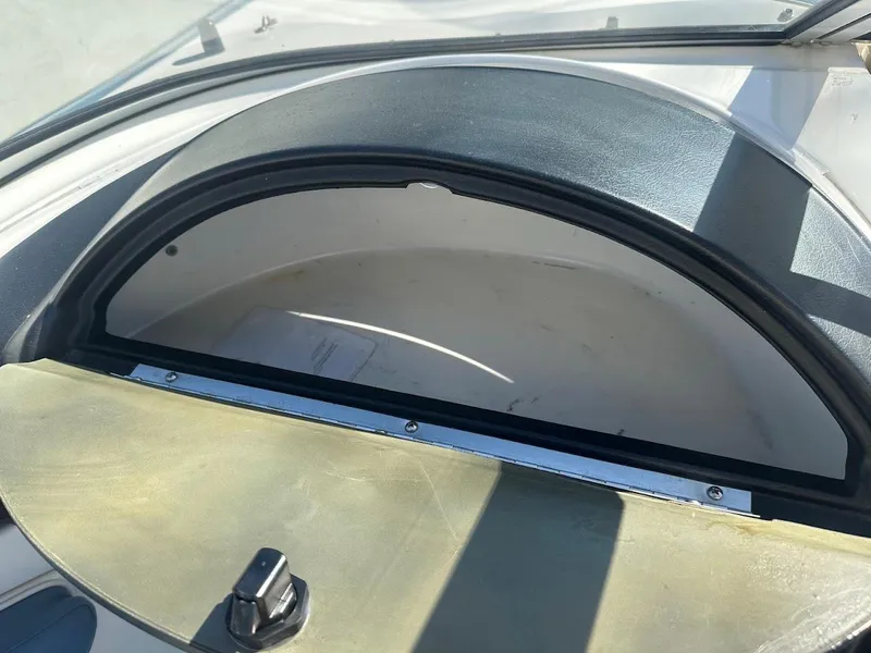 Slide: The Image of 2012 Bayliner 235 Bowrider dashboard compartment, open and empty, with sunlight casting shadows. - 19