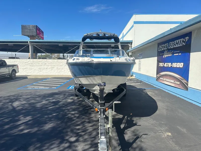 Slide: The Image of 2012 Bayliner 235 Bowrider on trailer, parked outdoors near a building. - 2