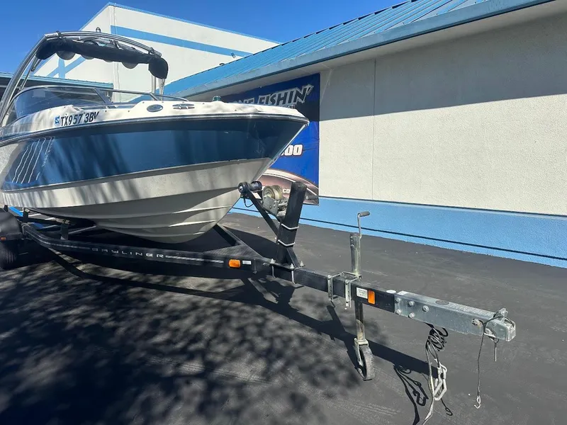 Slide: The Image of 2012 Bayliner 235 Bowrider on trailer, parked outside a building. - 3