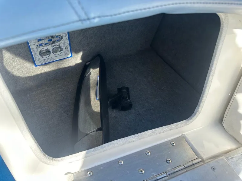 Slide: The Image of Storage compartment in a 2012 Bayliner 235 Bowrider boat, featuring a flashlight and manual. - 32