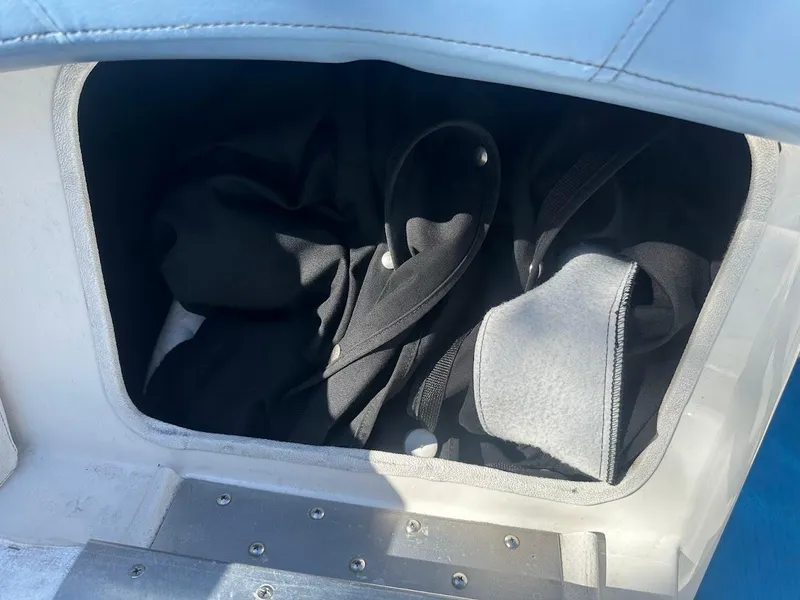 Slide: The Image of Storage compartment in a 2012 Bayliner 235 Bowrider boat, containing black fabric items. - 33