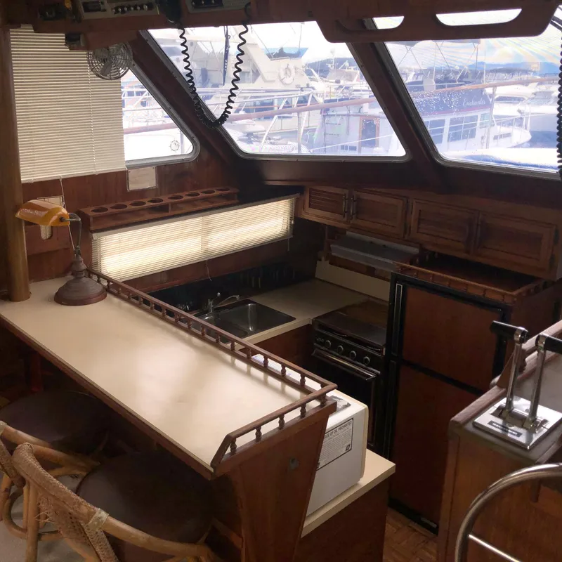 Slide: The Image of 1976 Tollycraft 48 Cockpit Motor Yacht interior with kitchen, wooden cabinets, and large windows. - 11