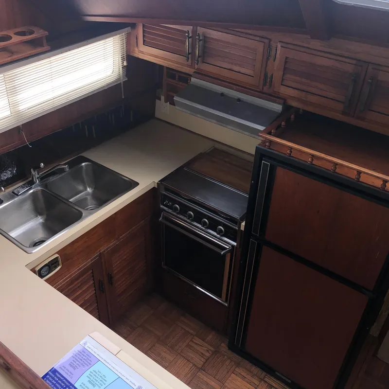Slide: The Image of 1976 Tollycraft 48 Cockpit Motor Yacht kitchen with wood cabinets, stove, and double sink. - 12