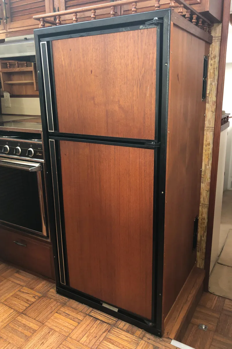 Slide: The Image of 1976 Tollycraft 48 Cockpit Motor Yacht interior with vintage wooden cabinetry and appliances. - 13