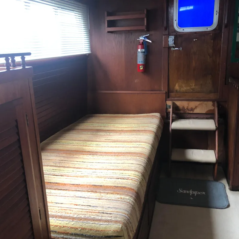 Slide: The Image of 1976 Tollycraft 48 Cockpit Motor Yacht interior with bed, wooden walls, and fire extinguisher. - 24