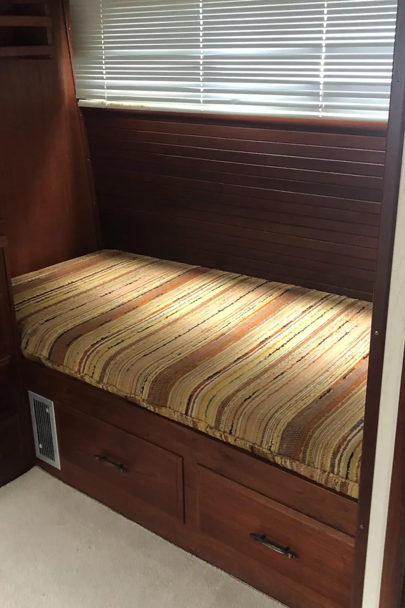Slide: The Image of 1976 Tollycraft 48 Cockpit Motor Yacht interior with striped cushion and wooden drawers. - 25