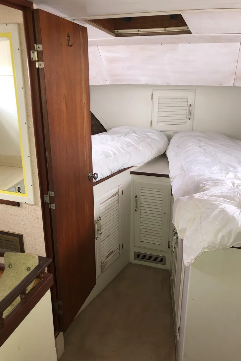Slide: The Image of 1976 Tollycraft 48 Cockpit Motor Yacht cabin with twin beds and wooden cabinetry. - 28