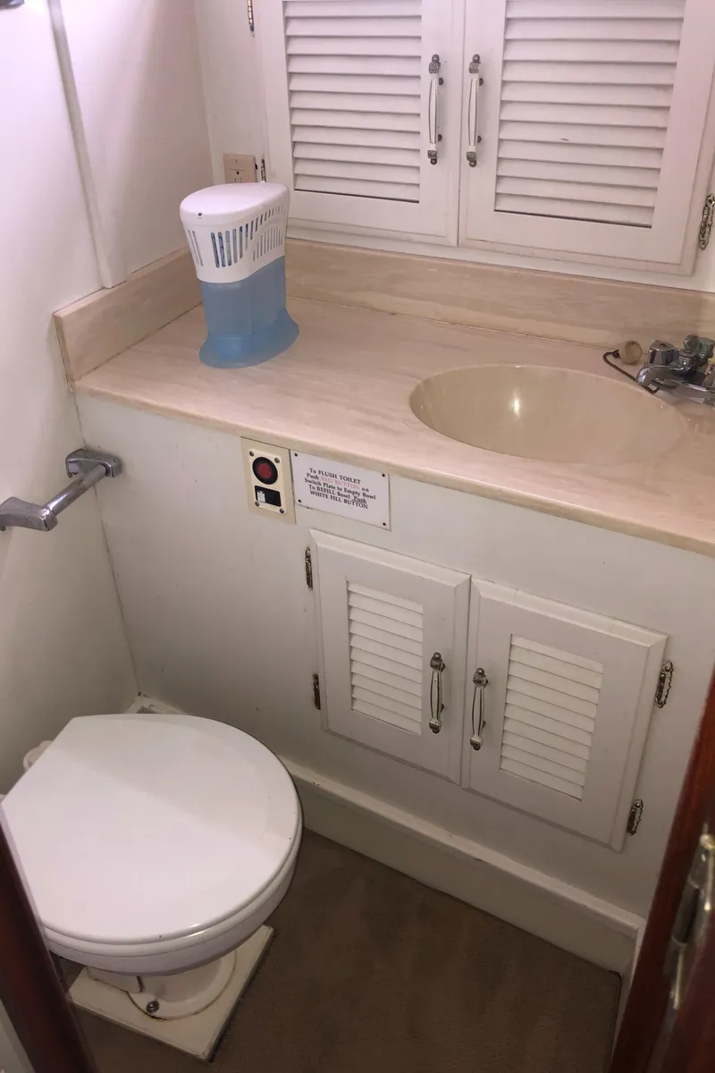Slide: The Image of 1976 Tollycraft 48 Cockpit Motor Yacht bathroom with sink, toilet, and storage cabinets. - 30