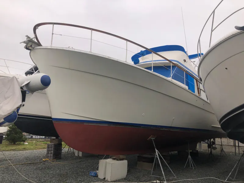 Slide: The Image of 1976 Tollycraft 48 Cockpit Motor Yacht on dry dock, white hull with blue accents. - 37