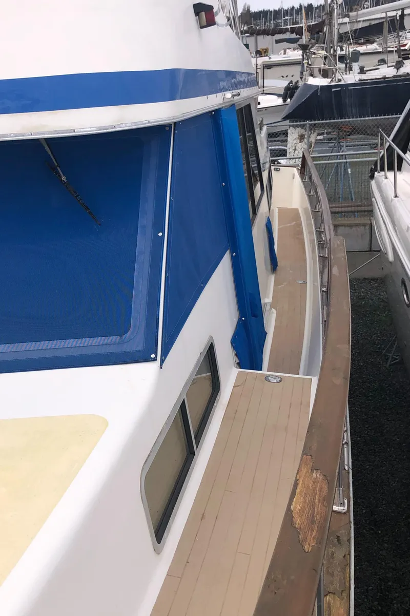 Slide: The Image of 1976 Tollycraft 48 Cockpit Motor Yacht docked, featuring blue accents and spacious deck. - 5