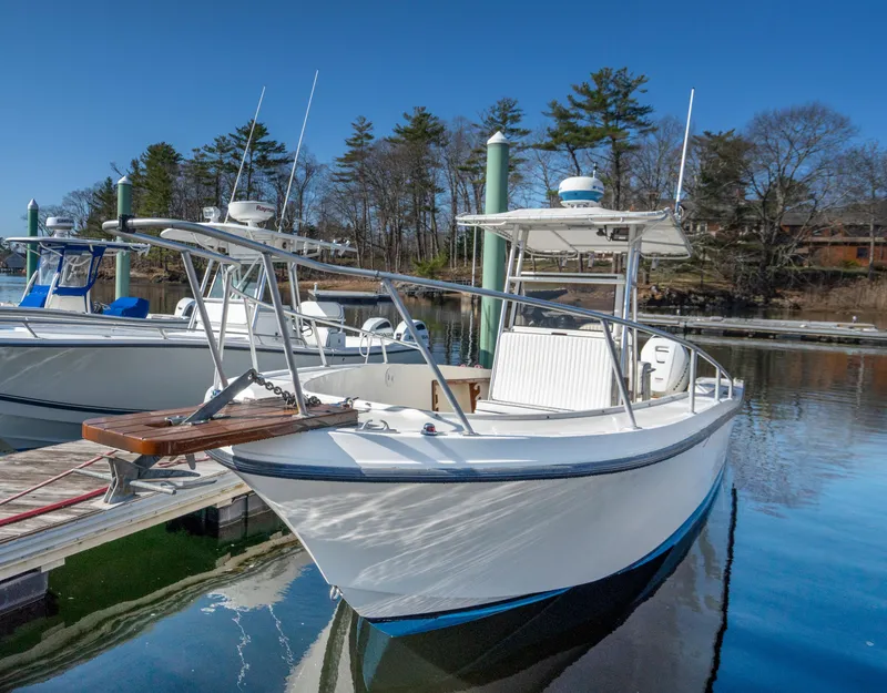 Slide: The Image of 1990 Mako 261 Center Console boat docked in a serene marina setting. - 15