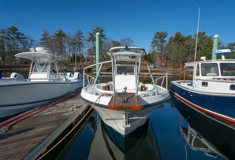 Slide: The Image of 1990 Mako 261 Center Console boat docked between two other boats. - 6